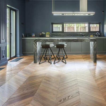 Fischgrät-Parkettboden in moderner Küche mit Bartresen und Hockern